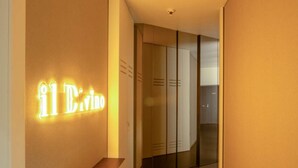 A hallway with a neon sign reading "il Drino" and a wooden bench. - il Divino (Naples)