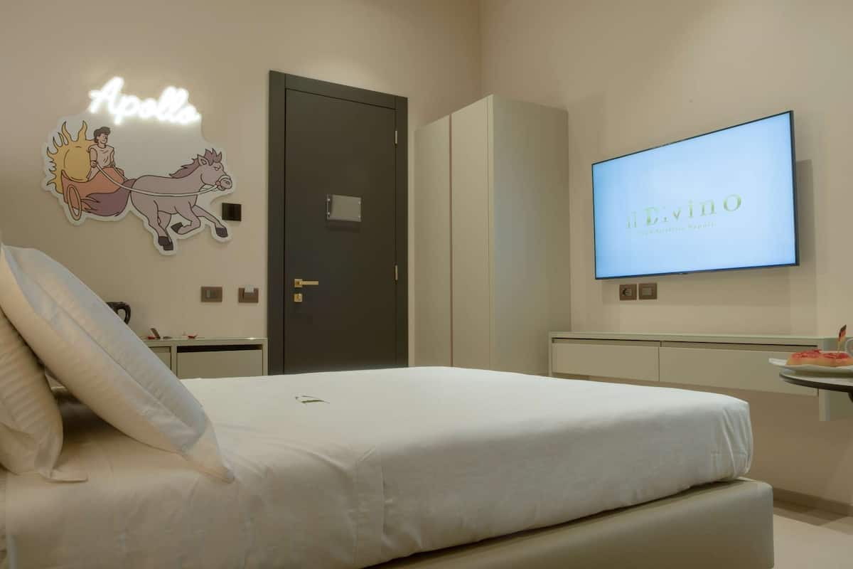 Un dormitorio con cama, televisor en la pared, una puerta y un letrero de neón.