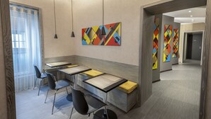 A modern hotel lobby with a long reception desk, black chairs, and colorful abstract wall art. - il Divino (Naples)