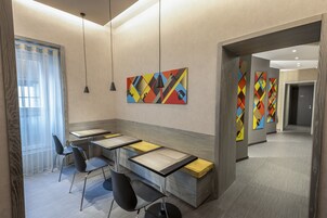 A modern hotel lobby with a long reception desk, black chairs, and colorful abstract wall art.
