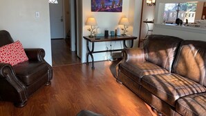 A living room with a brown leather sofa, a matching armchair, and a wooden coffee table. - You're going to love it here! (Virginia Beach)
