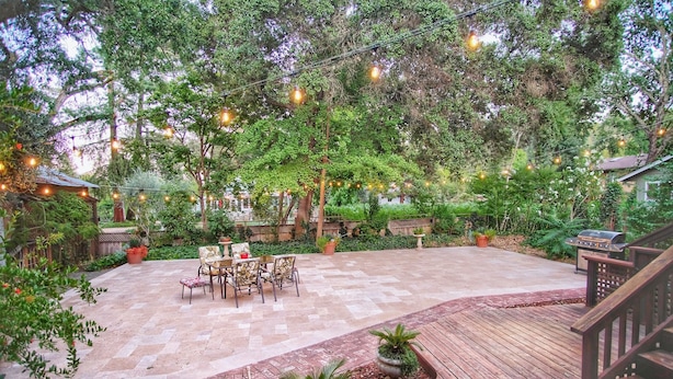 Ein Patio mit Holzboden, Gartenmöbeln und Lichterketten.