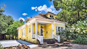 Ein gelbes Haus mit Veranda, Eingangstür und kleinem Garten.