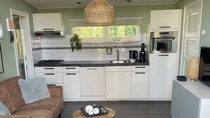 Una cocina moderna con armarios blancos, una isla central y una lámpara colgante.