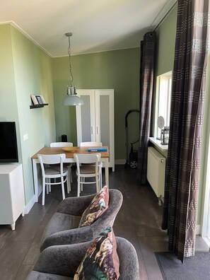 Un espace de vie compact comprenant un coin repas, un canapé, un téléviseur et un radiateur.
