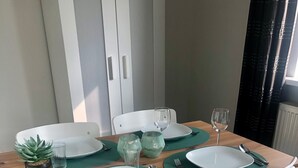 Una mesa de comedor dispuesta con platos blancos, individuales verdes y vasos transparentes.