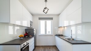 A modern kitchen with white cabinets, a black countertop, a built-in oven, a gas stove, and a window above the sink. - Villa Maja (Konavle)