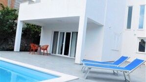 A modern two-story building with a swimming pool, outdoor seating, and a covered patio area. - Villa Maja (Konavle)