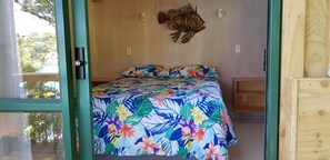 Una habitación con una cama que presenta un edredón floral, un cabecero de madera y una decoración de peces colgada en la pared.