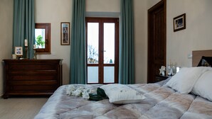 Ein Schlafzimmer mit einem Bett, einem Schminktisch, einem Spiegel und einer Tür mit Vorhängen.