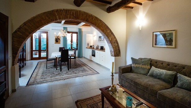 Ein Wohnzimmer mit einer Couch, ein Essbereich mit Tisch und Stühlen sowie eine Küche im Hintergrund.