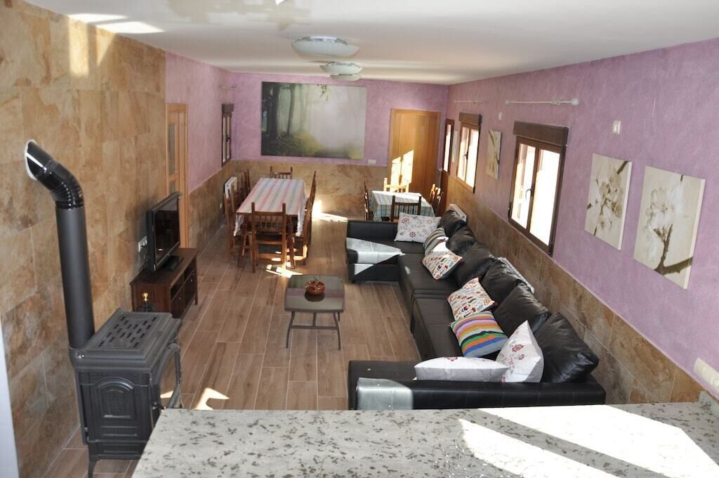 A living room with a fireplace, a sofa, a dining table, and a TV.