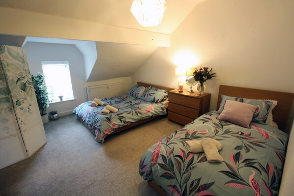 A bedroom with two beds, a dresser, a mirror, and a window. - Lymm village apartment (Lymm)