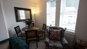 A dining area with a round table, chairs, and a zebra-patterned armchair. - Lymm village apartment (Lymm)