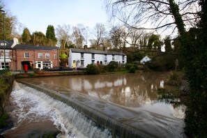 A river flowing through a town with buildings on both sides. - Lymm village apartment (Lymm)
