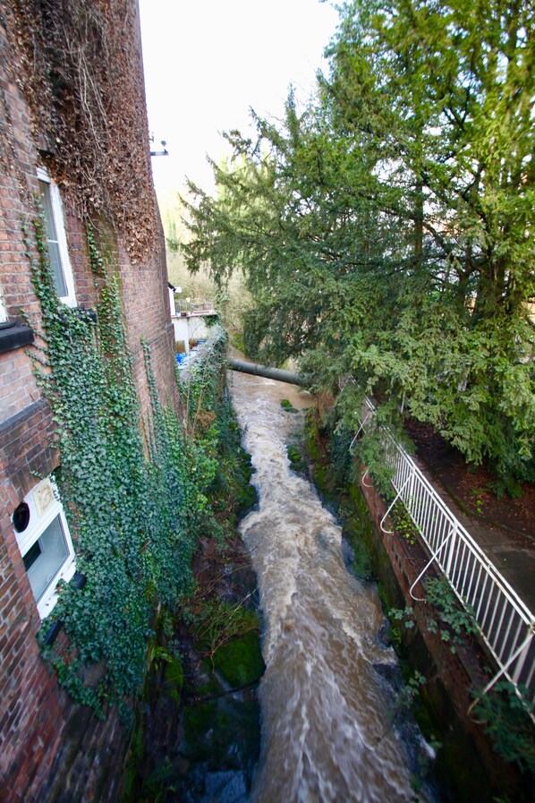 A narrow water channel with a brick building on one side and a metal railing on the other.