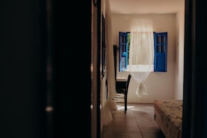 A room with a bed, a chair, and a window with blue shutters. - Pousada Nel Blu (Itaparica)