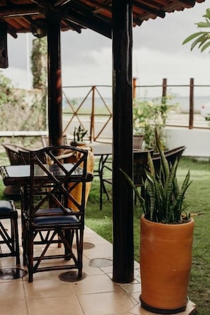 An outdoor patio area with wooden furniture and potted plants. - Pousada Nel Blu (Itaparica)
