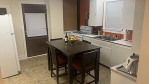 A compact kitchen with a dining table and chairs, a refrigerator, a stove, and a sink. - Beaumont Nurses or Dr’s need quarantine site?<br>Downtown Royal Oak, charming 2bd (Royal oak)