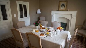 Ein Esszimmer mit gedecktem Tisch für das Frühstück, darunter Teller mit Speisen, eine Karaffe und eine Blumenvase.
