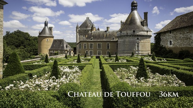Chateau de Touffou, ein historisches Schloss mit einem gepflegten Garten und einem großartigen Steinhaus mit mehreren Türmen.