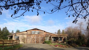 A rustic barn with a large garage door, surrounded by a gravel driveway and a wooden fence. - 40 Acres Estate, Beach Access, Pet Friendly: Wildwood Studio (Vashon)