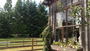 A rustic wooden building with a stone foundation, large windows, and a wooden fence. - 40 Acres Estate, Beach Access, Pet Friendly: Wildwood Studio (Vashon)