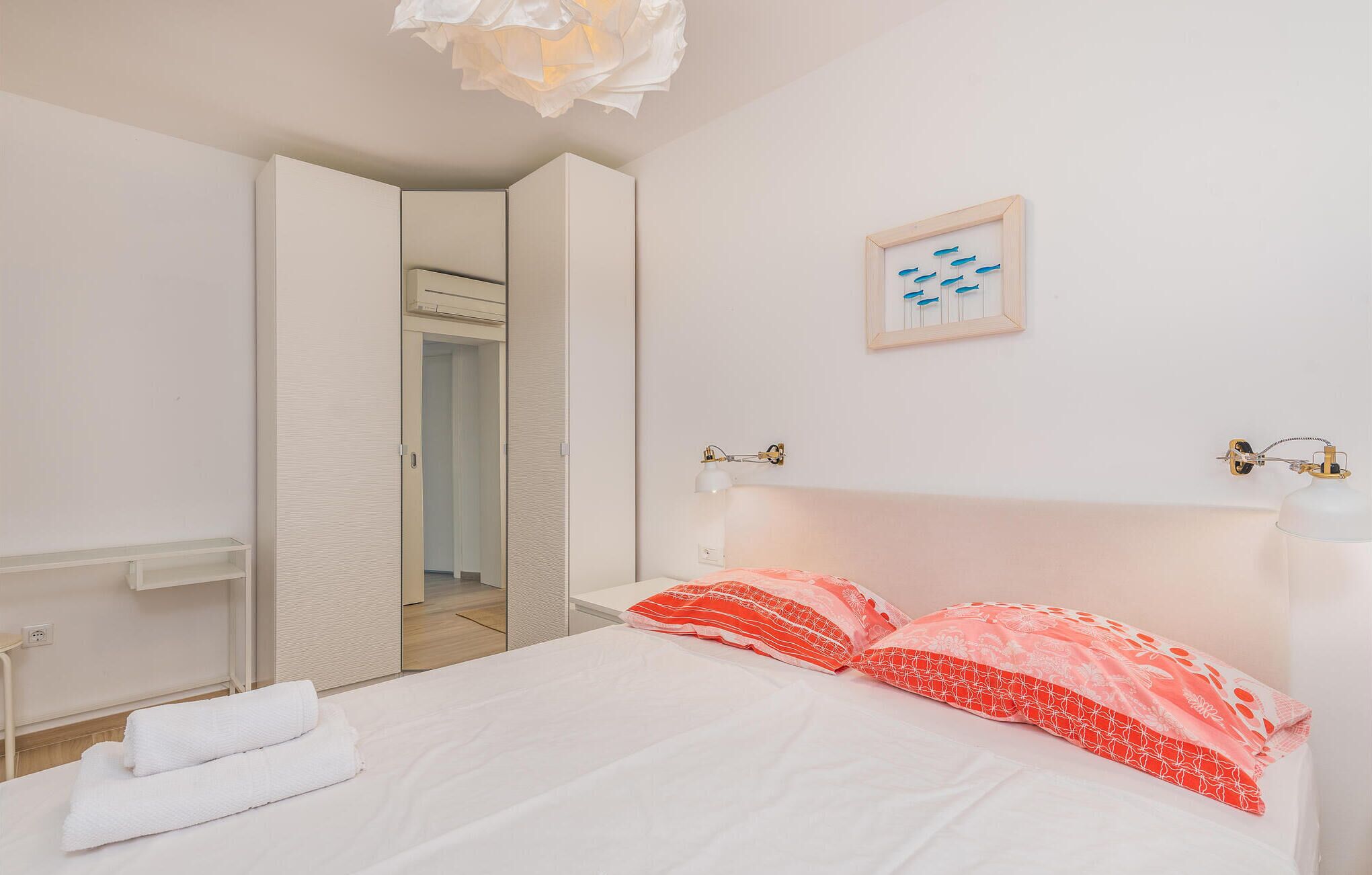 Ein Schlafzimmer mit einem Bett, einem Nachttisch, einem Spiegel und einer Wandleuchte.