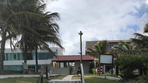 A staircase leading to a building with a red-tiled roof, surrounded by palm trees and greenery. - Porto de Galinhas House in Cond. by the sea Esmeralda do Mar (Ipojuca)