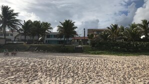 A sandy beach with palm trees and buildings in the background. - Porto de Galinhas House in Cond. by the sea Esmeralda do Mar (Ipojuca)