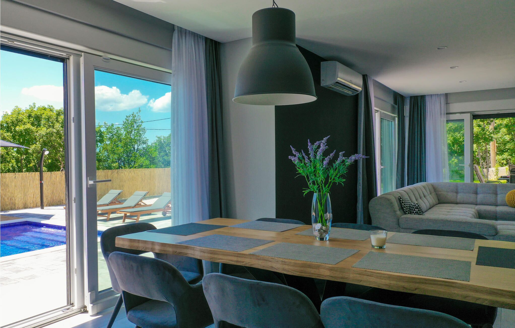 A modern dining area with a large table, chairs, and a vase of flowers.