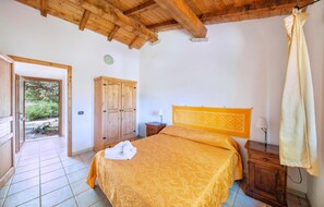 A bedroom with a bed, wooden wardrobe, bedside table, and a curtain. - Awesome apartment in Badesi with swimming pool (Badesi)