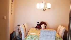 A dining area with a chandelier, floral tablecloth, and a stuffed toy on the table. - Waterfront Paradise condo (Bradenton)