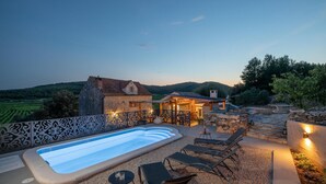 Un espace piscine avec des chaises longues et un mur en pierre.