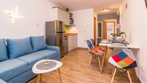 A compact living space with a sofa, a small dining table with chairs, a kitchenette, and a door leading to another room. - Nice apartment in Pula with house sea view (Pula)