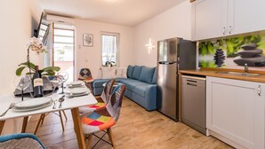 A compact living space with a dining area, a sofa, a kitchen with a dishwasher, and a small dining table with chairs. - Nice apartment in Pula with house sea view (Pula)