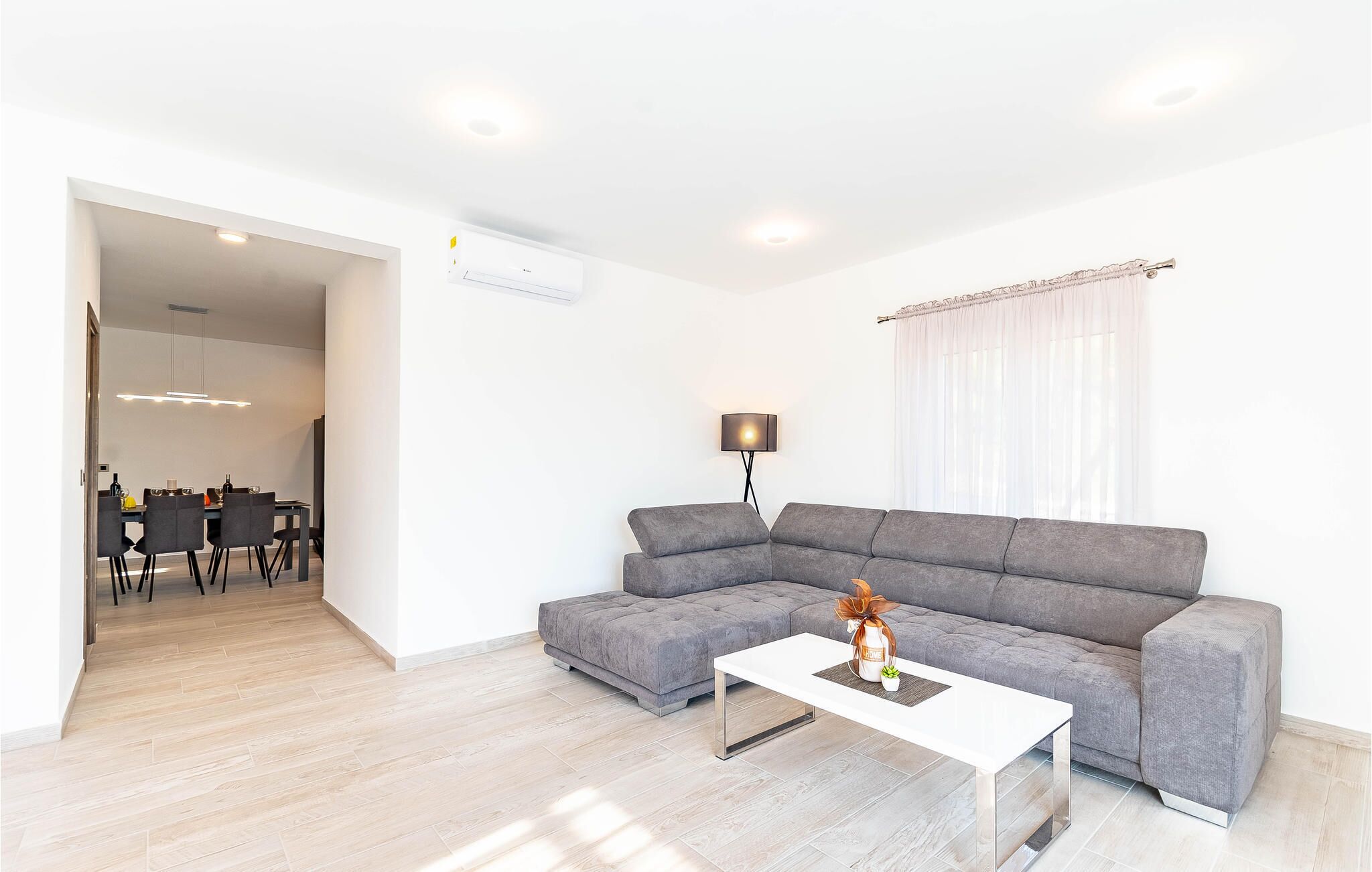 A modern living room with a grey sectional sofa, a white coffee table, and a floor lamp.