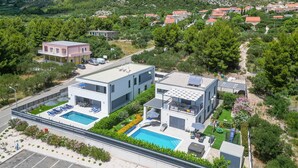 A modern two-story building with a rooftop pool and solar panels.