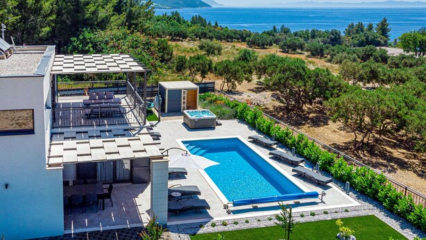A modern villa with a rooftop terrace, a swimming pool, and a view of the sea.