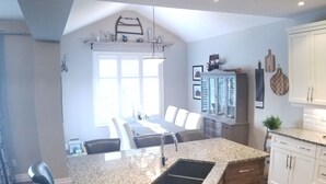 A kitchen with a granite countertop, a sink, and a dining area with a table and chairs.