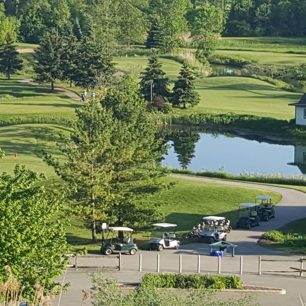 Un parcours de golf avec un étang, des arbres et un club-house.