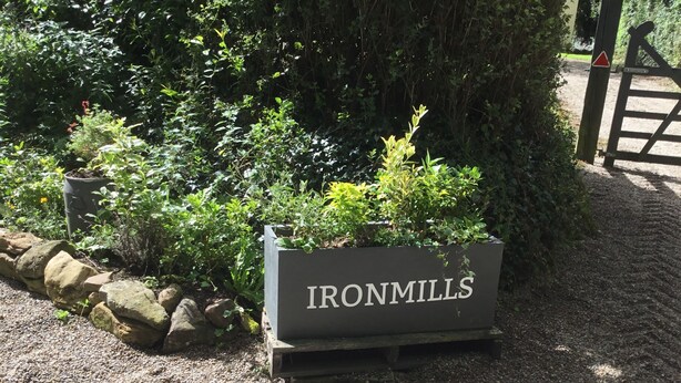 A sign labeled "IRONMILLS" in a garden setting with gravel paths and greenery. - COZY FARMHOUSE COTTAGE with wonderful views, FREE Fibre Broadband (Cappawhite)