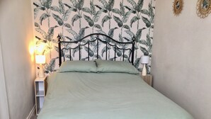 A neatly made bed with a green bedspread and pillows, a black metal headboard, and two bedside lamps on wooden nightstands. - COZY FARMHOUSE COTTAGE with wonderful views, FREE Fibre Broadband (Cappawhite)