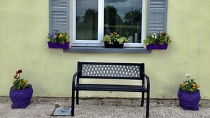 A bench in front of a window with shutters, flanked by two purple flower pots. - COZY FARMHOUSE COTTAGE with wonderful views, FREE Fibre Broadband (Cappawhite)