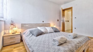 Une chambre à coucher avec une tête de lit en bois, une table de chevet avec une lampe, deux oreillers et deux serviettes enroulées sur le lit.