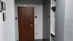 A hallway with a wooden door, a grey wardrobe, and a tiled floor. - Academy's Modern Apartment (Athens)