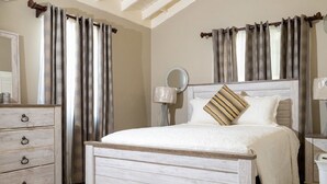Une chambre à coucher avec un lit en bois, une commode, une table de chevet avec une lampe et des rideaux.