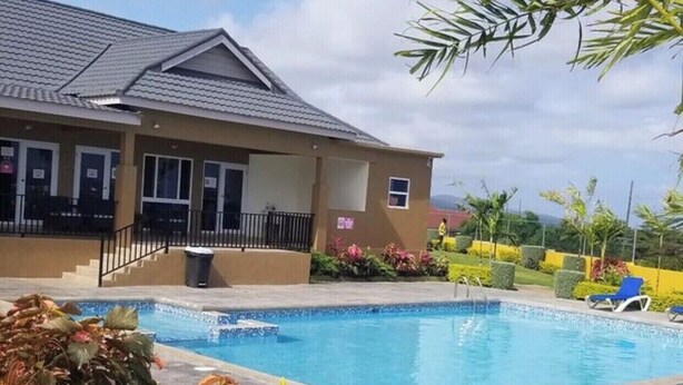 Une propriété résidentielle dotée d’une piscine, d’un patio couvert et d’un jardin aménagé.