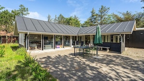 A covered patio area with a table and chairs, a bench, and a green umbrella. - 4 bedroom beautiful home in Vestervig (Vestervig)