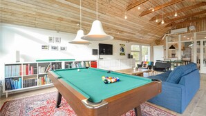 A pool table in a room with a wooden ceiling, a sofa, and a bookshelf with books. - 4 bedroom beautiful home in Vestervig (Vestervig)
